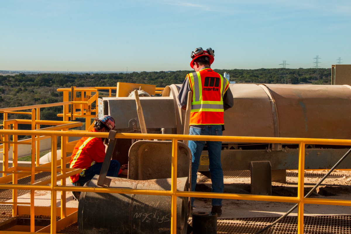 Workers inspect a belt conveyor.