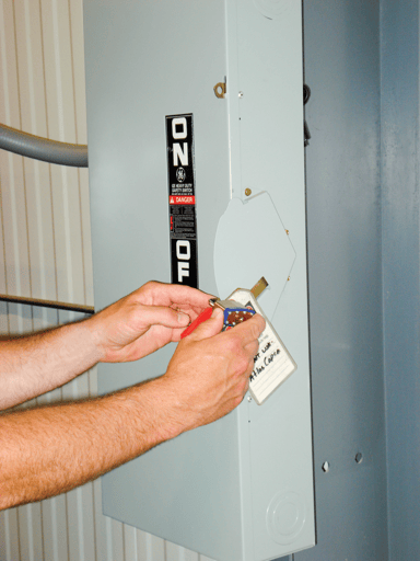 A man attaches his padellock to a lockout/tagout board.