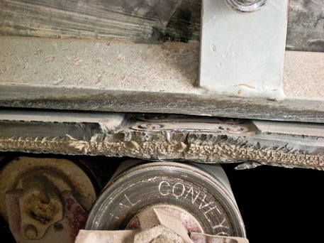 A close-up view of the conveyor belt shows the fasteners have been recessed into the belt top cover.