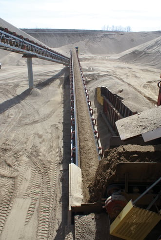 Sand is carried on a conveyor belt in a sand pit.