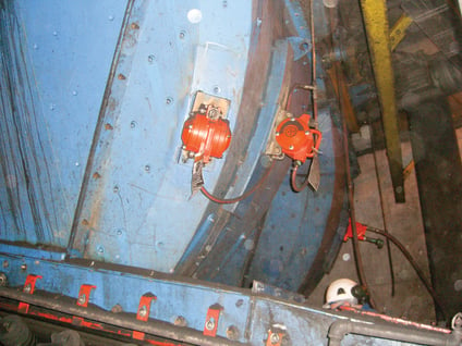 A piston vibrator is mounted on the side of a transfer chute.