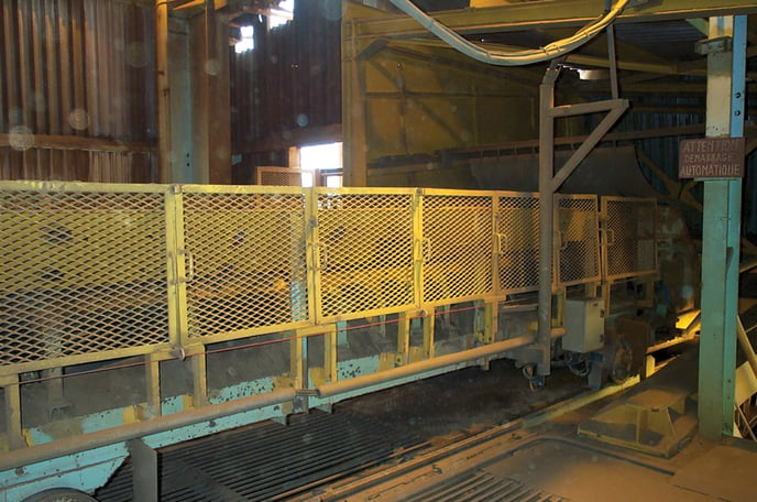 A fence-style metal barrier is attached to a belt conveyor.