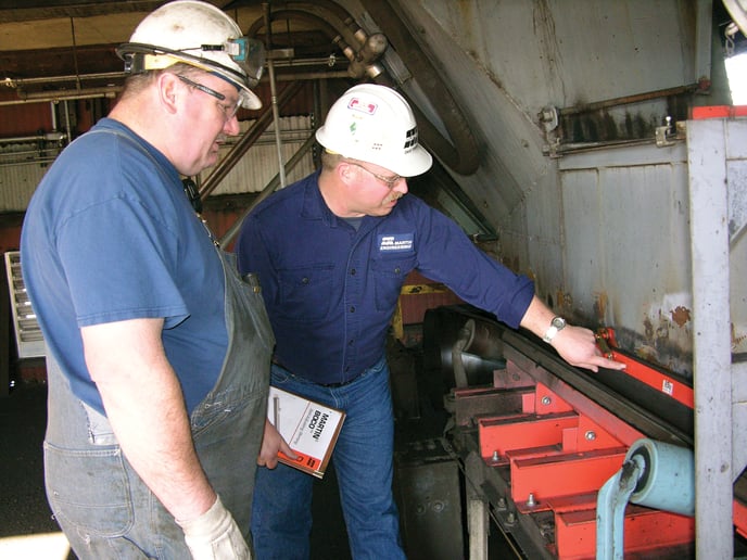 A vendor assists a worker in reviewing his conveyor system.