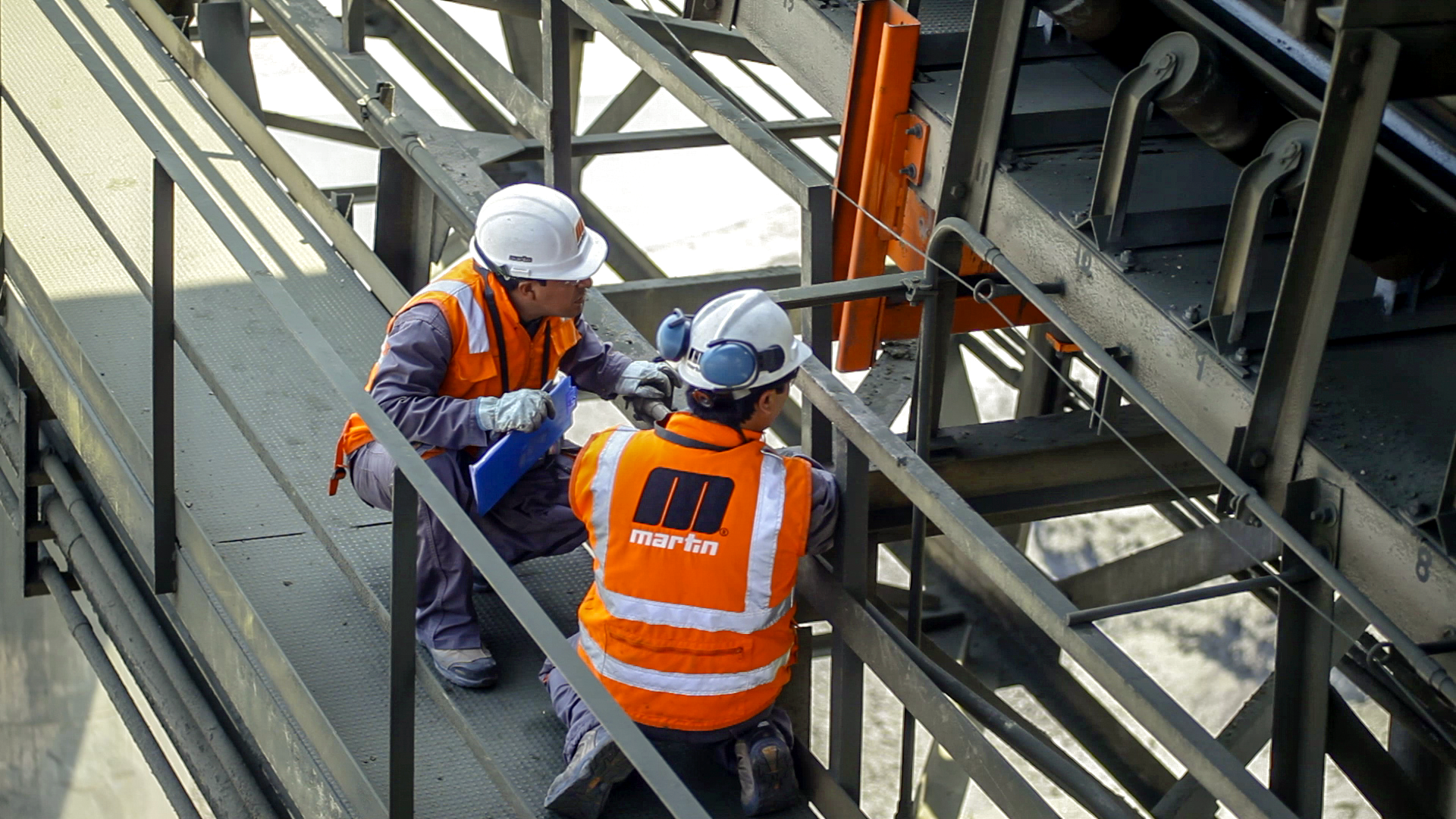 Workers inspecting a belt conveyor system.