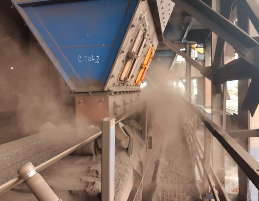 Airborne dust escaping from a belt conveyor transfer point.