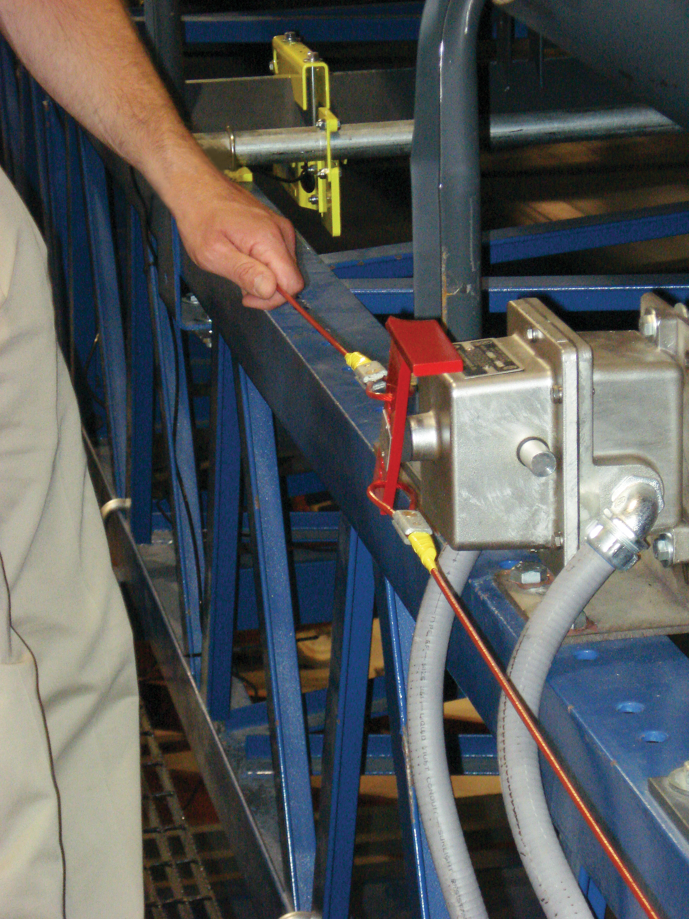A worker pulling a belt conveyor emergency stop switch.