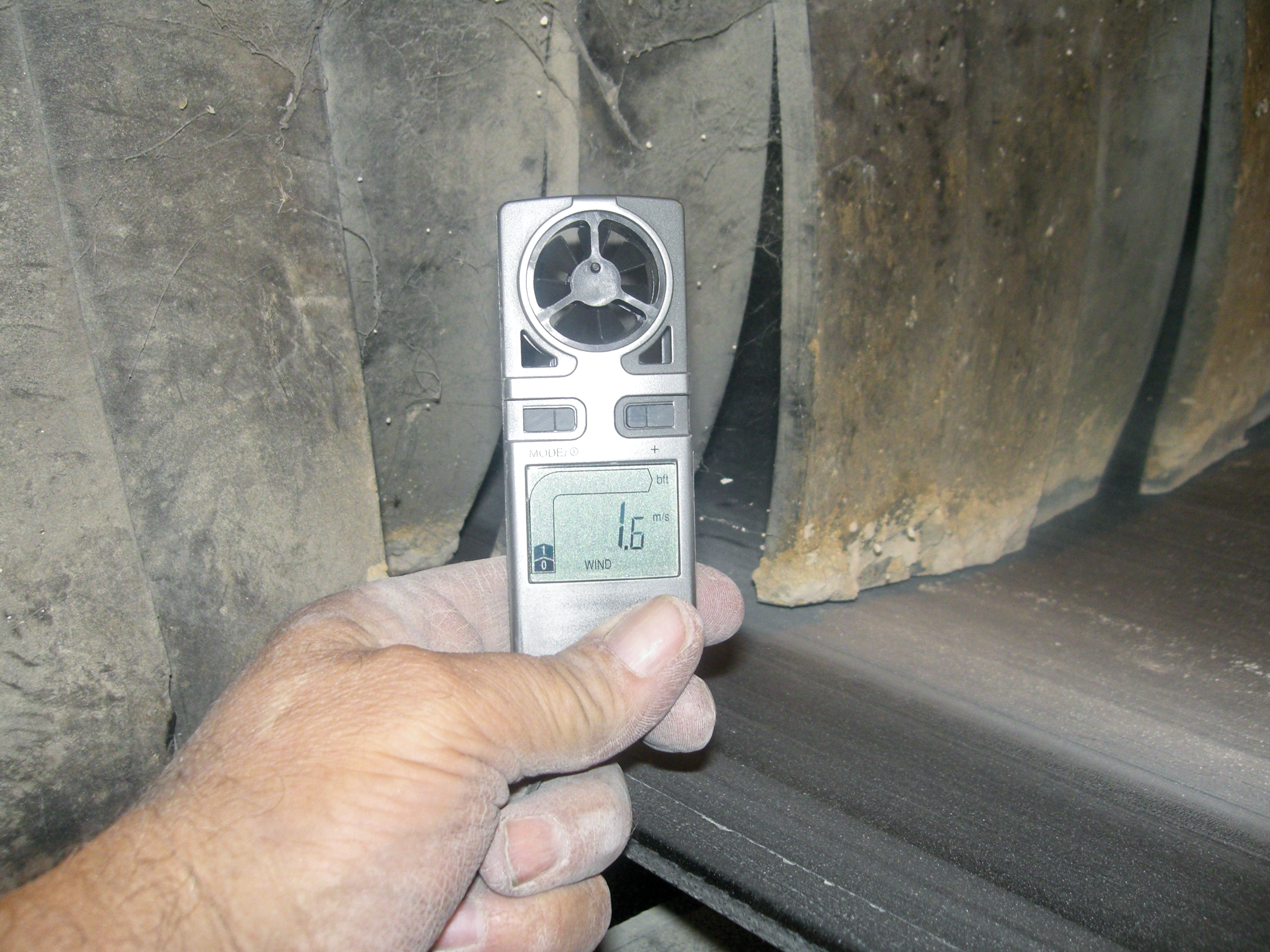 Air velocity is measured at a dust curtain at the exit of a belt conveyor transfer point settling zone.