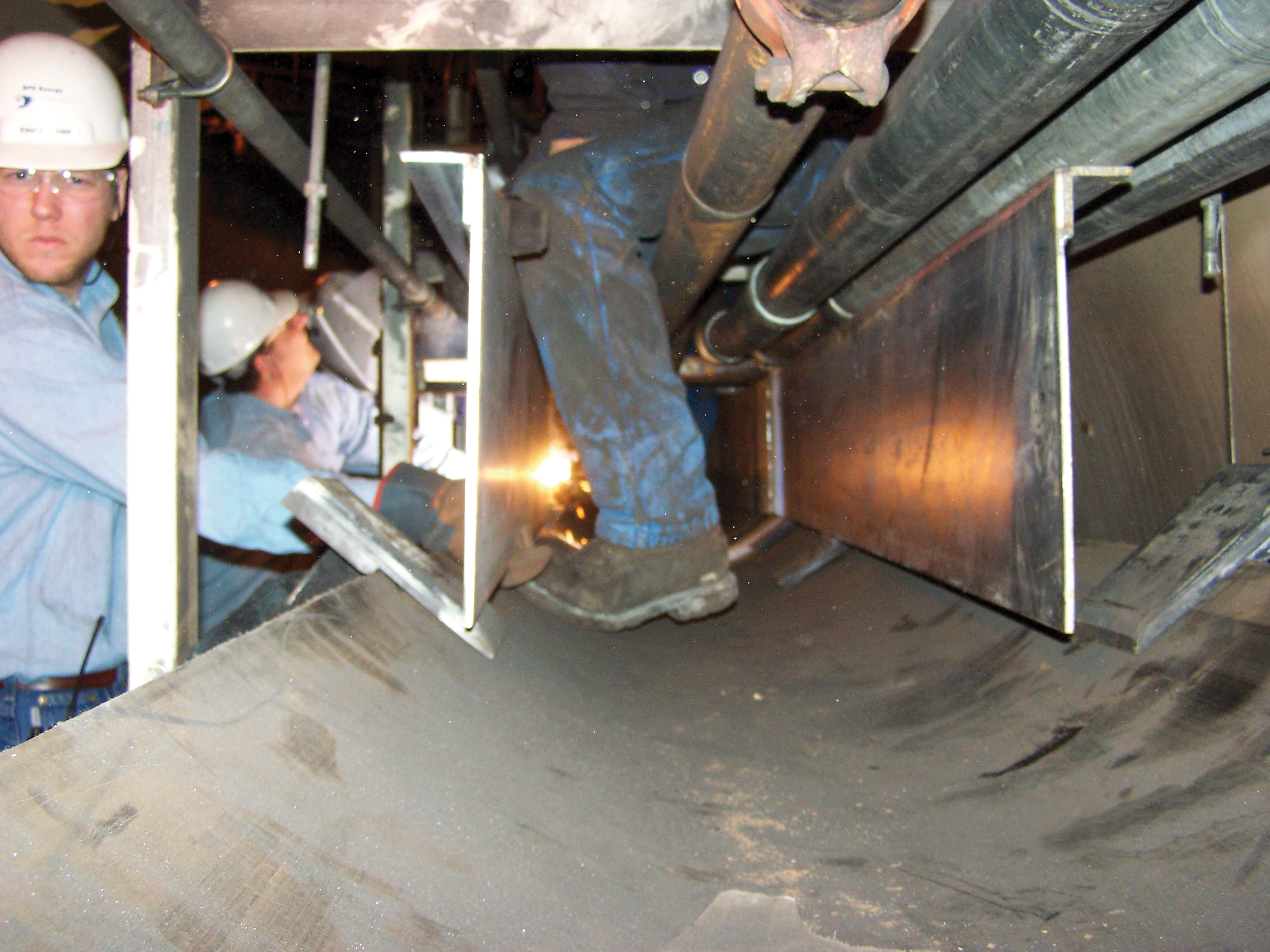 Workers install skirtboard in a belt conveyor load and settling zone.