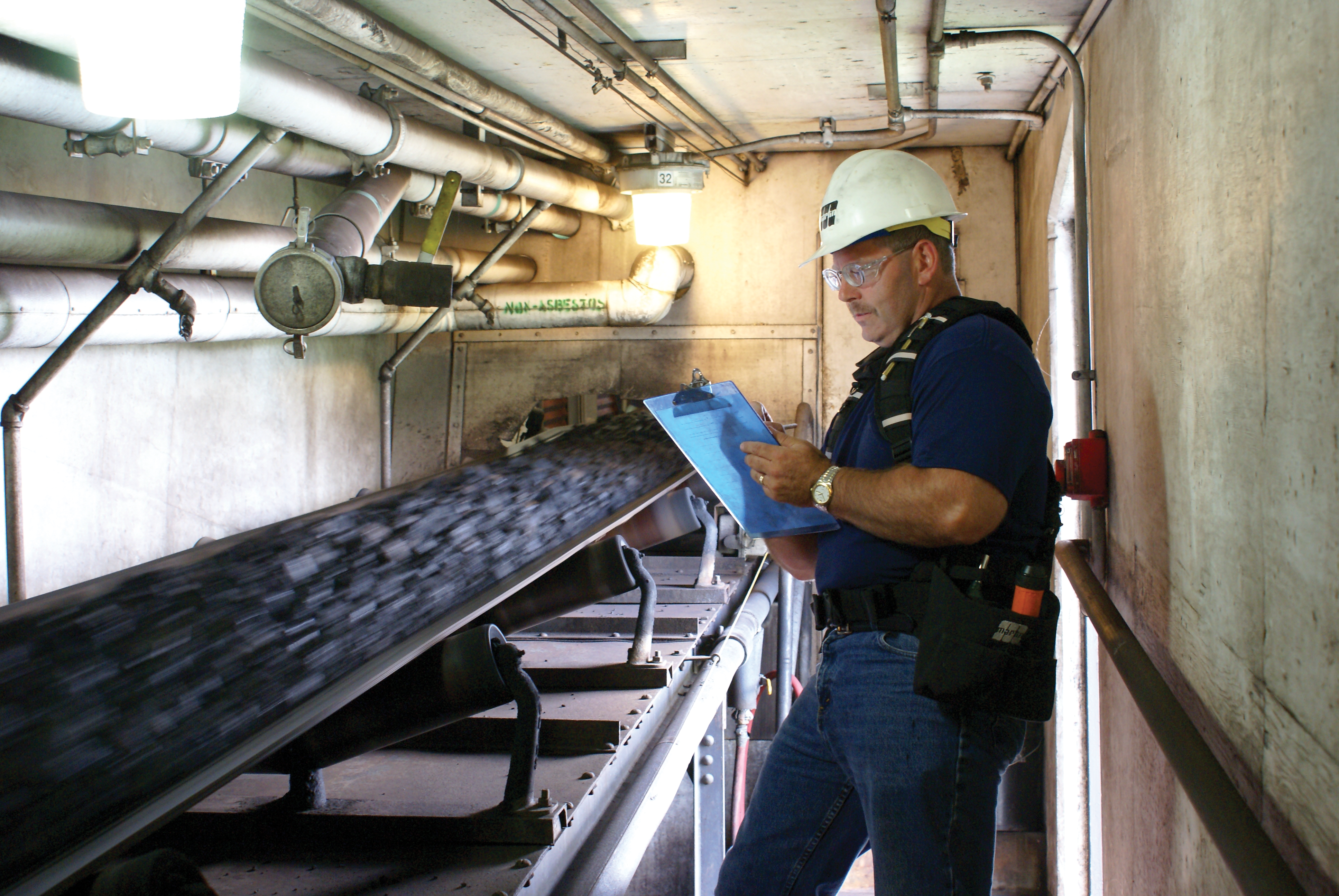 A consultant inspects a belt conveyor system in operation.