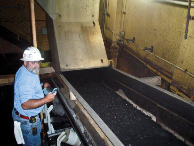 Worker inspecting a belt conveyor transfer point.