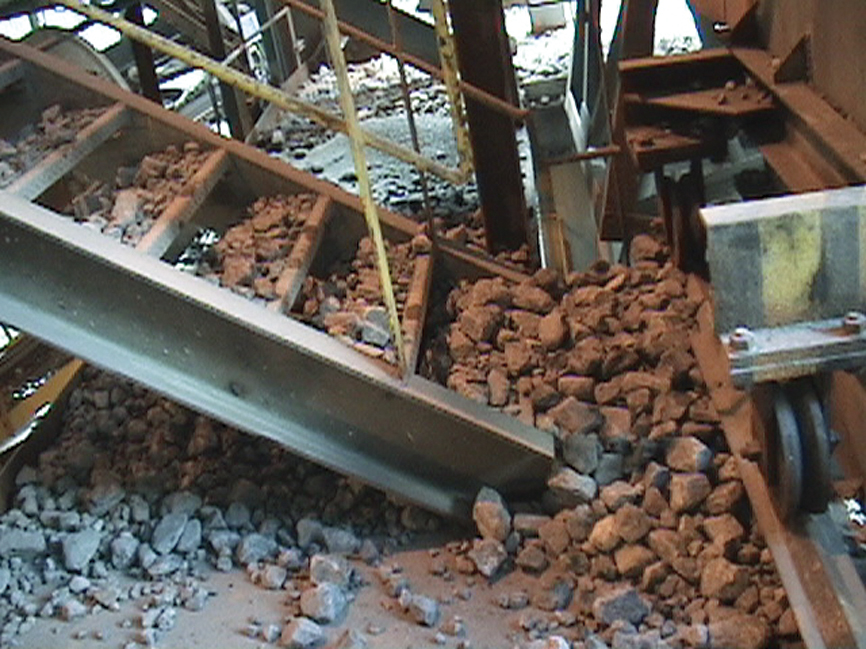 The bottom of a stairway shows piles of rocks and sand.
