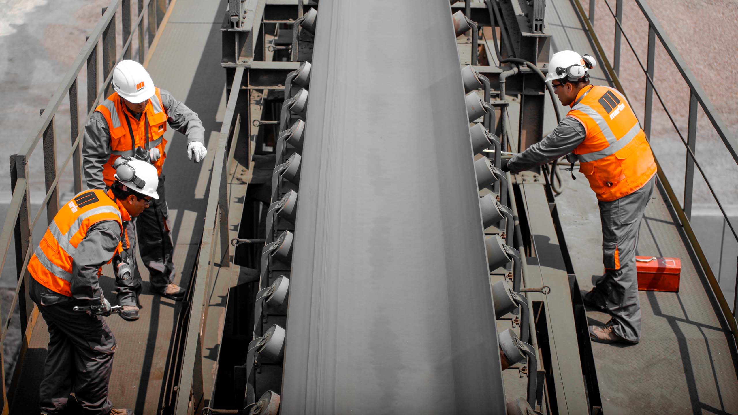 Workers inspect a belt conveyor system.